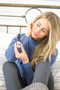 Woman lays in bed with Pure CBD to prepare her body for sleep.
